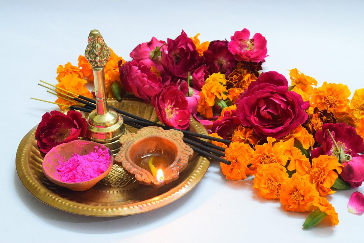 Marigold flowers and a lit diya arranged on a puja thali