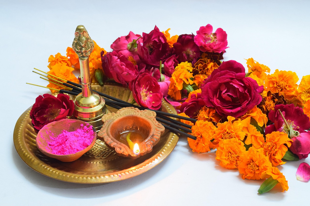 Marigold flowers and a lit diya arranged on a puja thali